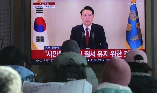 12月12日,在韩国首尔火车站,韩国民众观看总统尹锡悦对国民谈话的电视直播。新华社记者 姚琪琳 摄